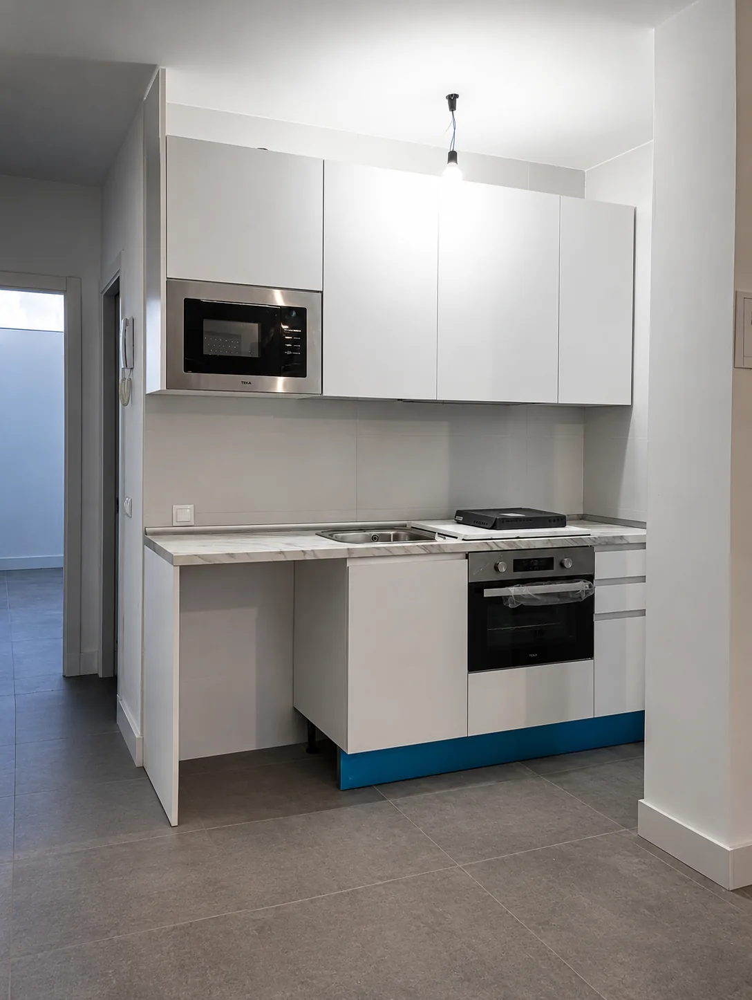 Cocina blanca con horno, microondas y encimera montada